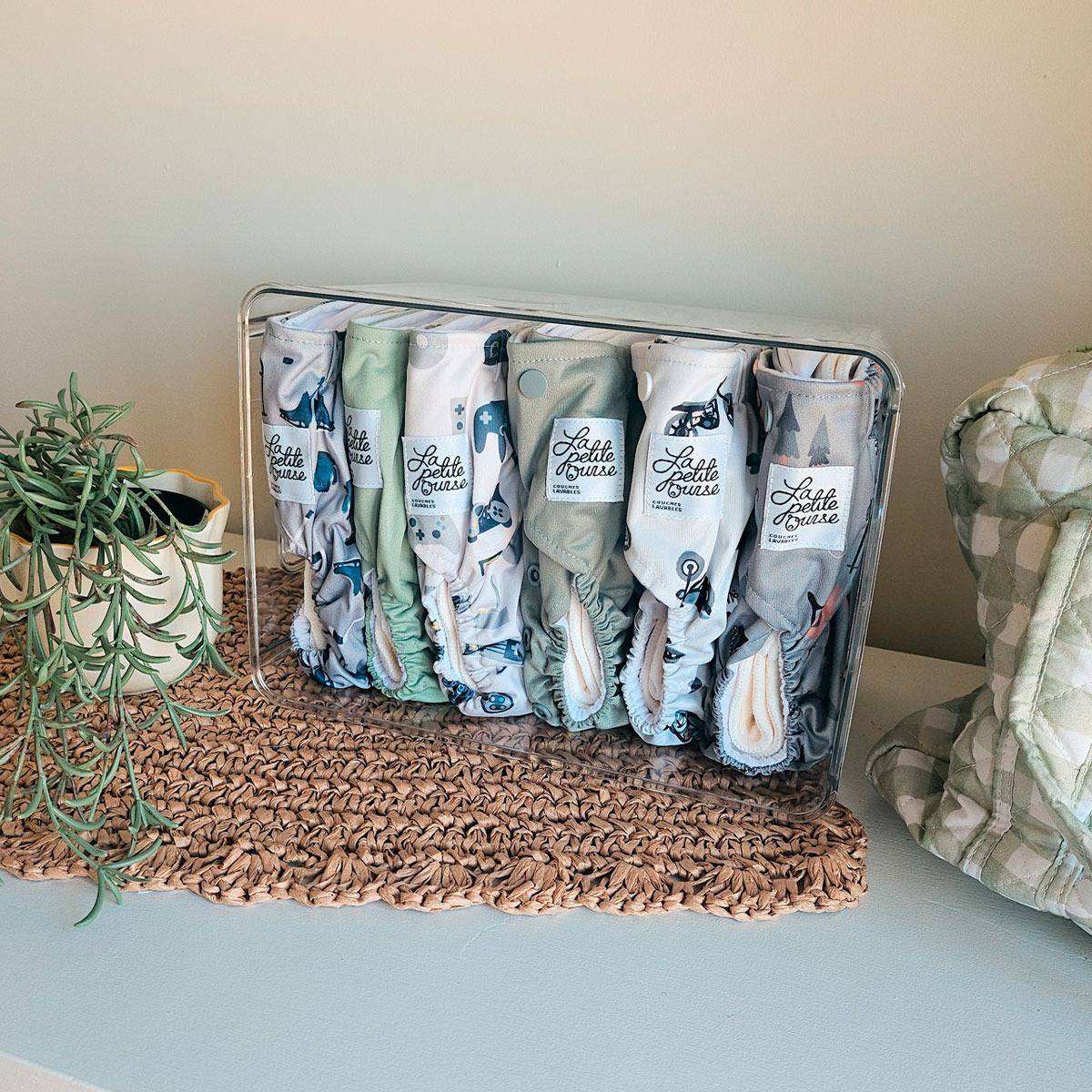 La Petite Ourse EVOLUTION cloth diapers lined up in a clear bin